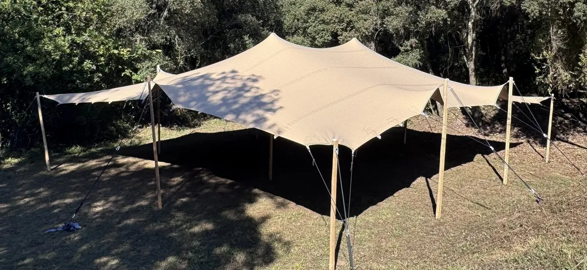 Carpa beduïna estesa sobre un prat sec, amb el bosc al darrere