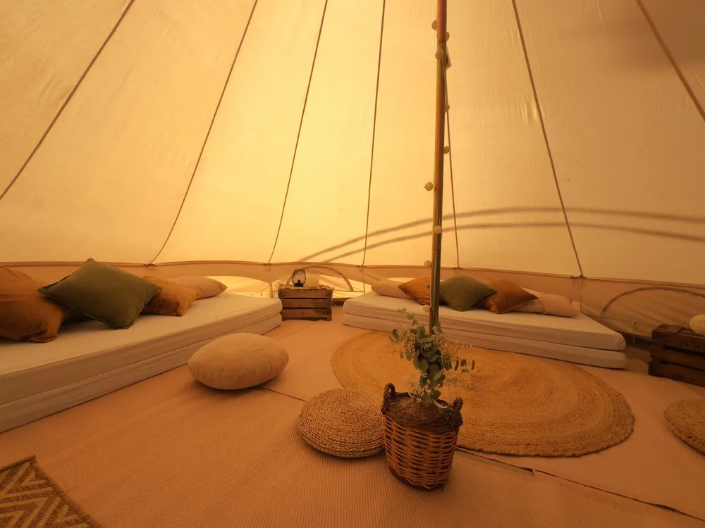 Racó chill-out dins d'un tipi amb coixins, tauletes baixes i llum ambre