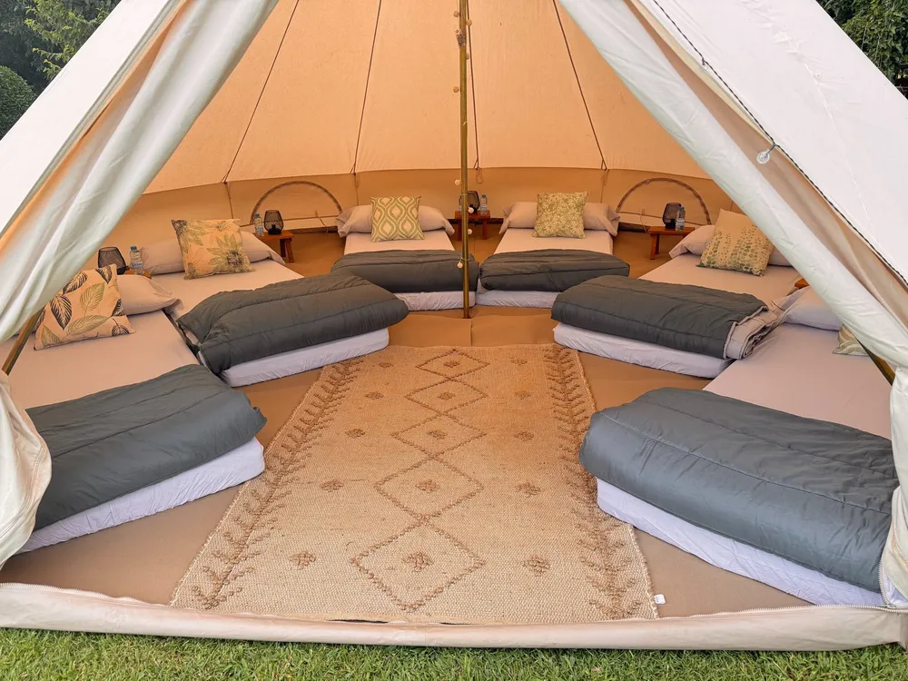 Interior d'un tipi gran amb matalassos i coixins disposats en cercle sobre una catifa boho
